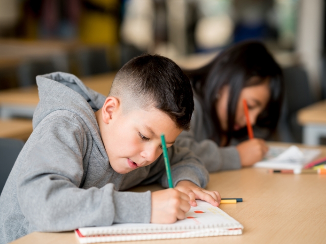 Two kids studying next to one another.