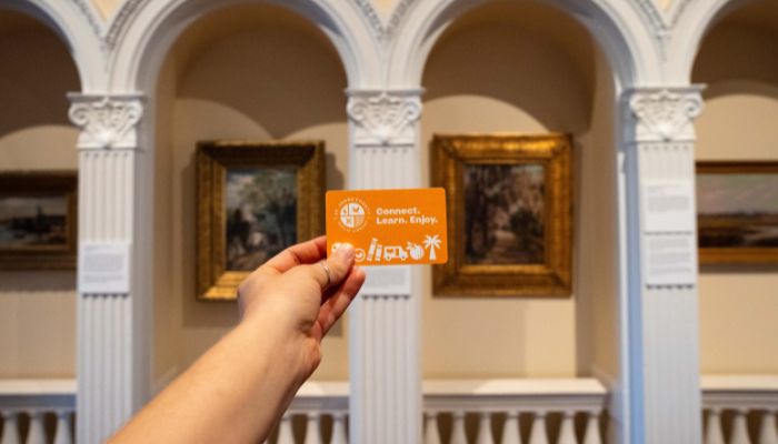 A hand holds an orange card reading 